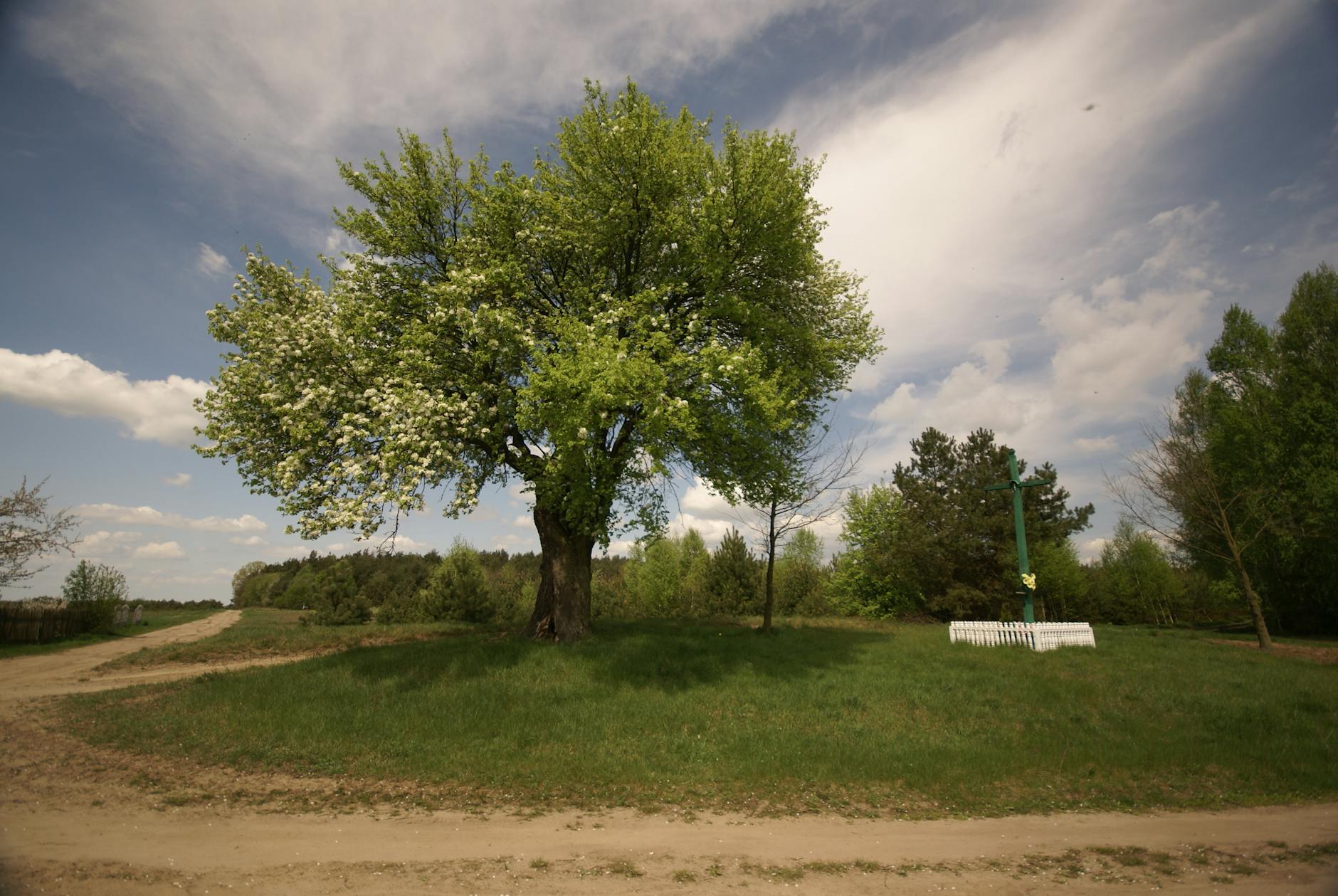 Uliczka Siemiatycz ozdobiona flagami narodowymi podczas majówki, z ludźmi spacerującymi i cieszącymi się wiosenną pogodą.